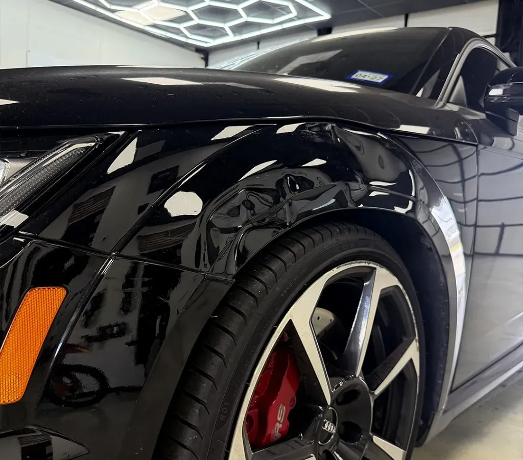 Dent in the front fender of a black Audi RS — before