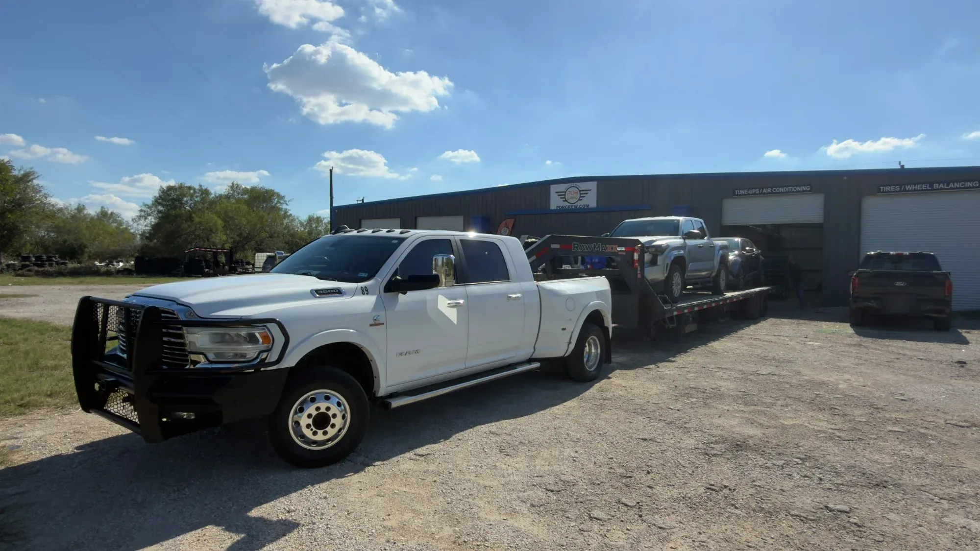 PDR Crew pickup towing a trailer loaded with vehicles into the shop