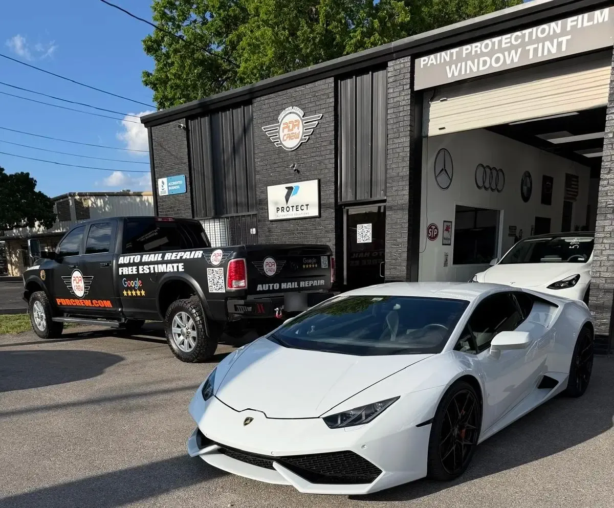 PDR Crew Austin shop front with the logo sign, the PDR Crew Auto Hail Repair truck and a white Lamborghini Huracán