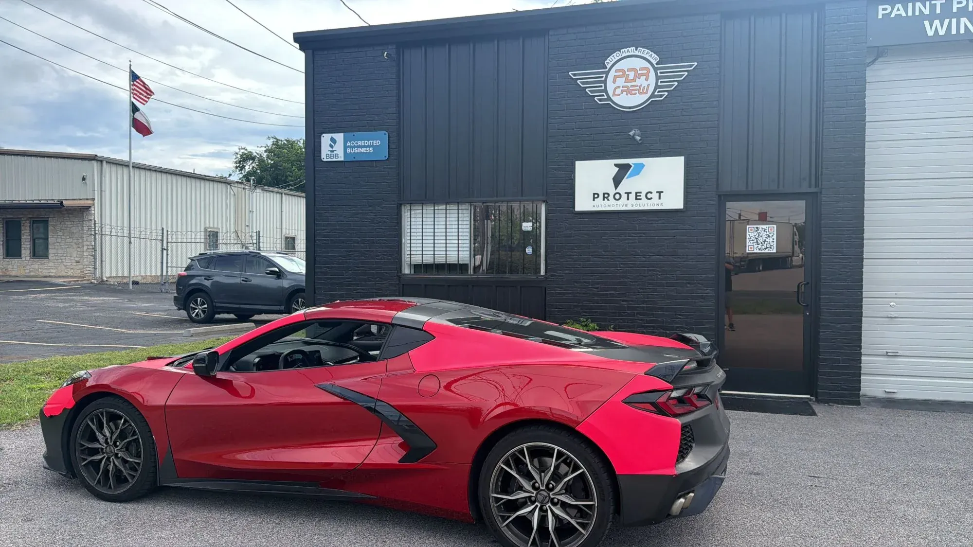 PDR Crew Austin shop front with the logo sign, BBB Accredited Business plaque and a red Corvette parked outside