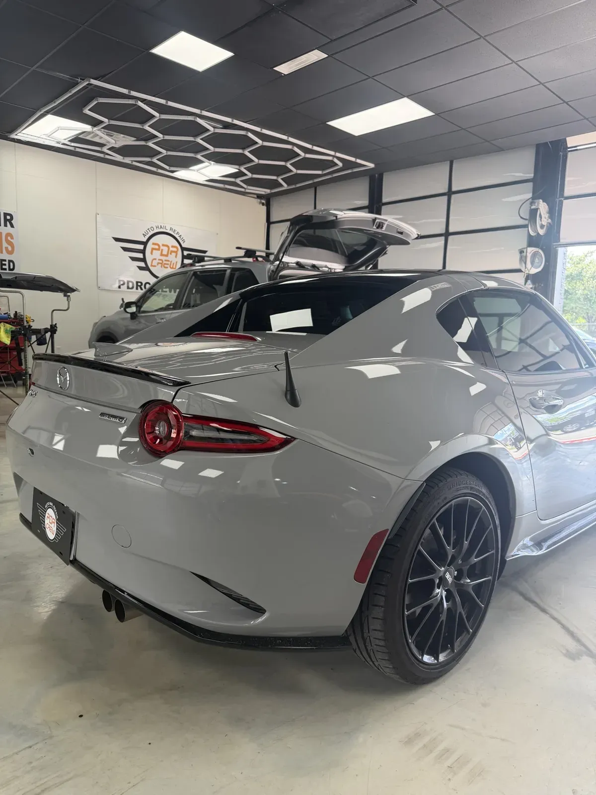 Gray Mazda MX-5 RF under the hexagon lights in the PDR Crew shop