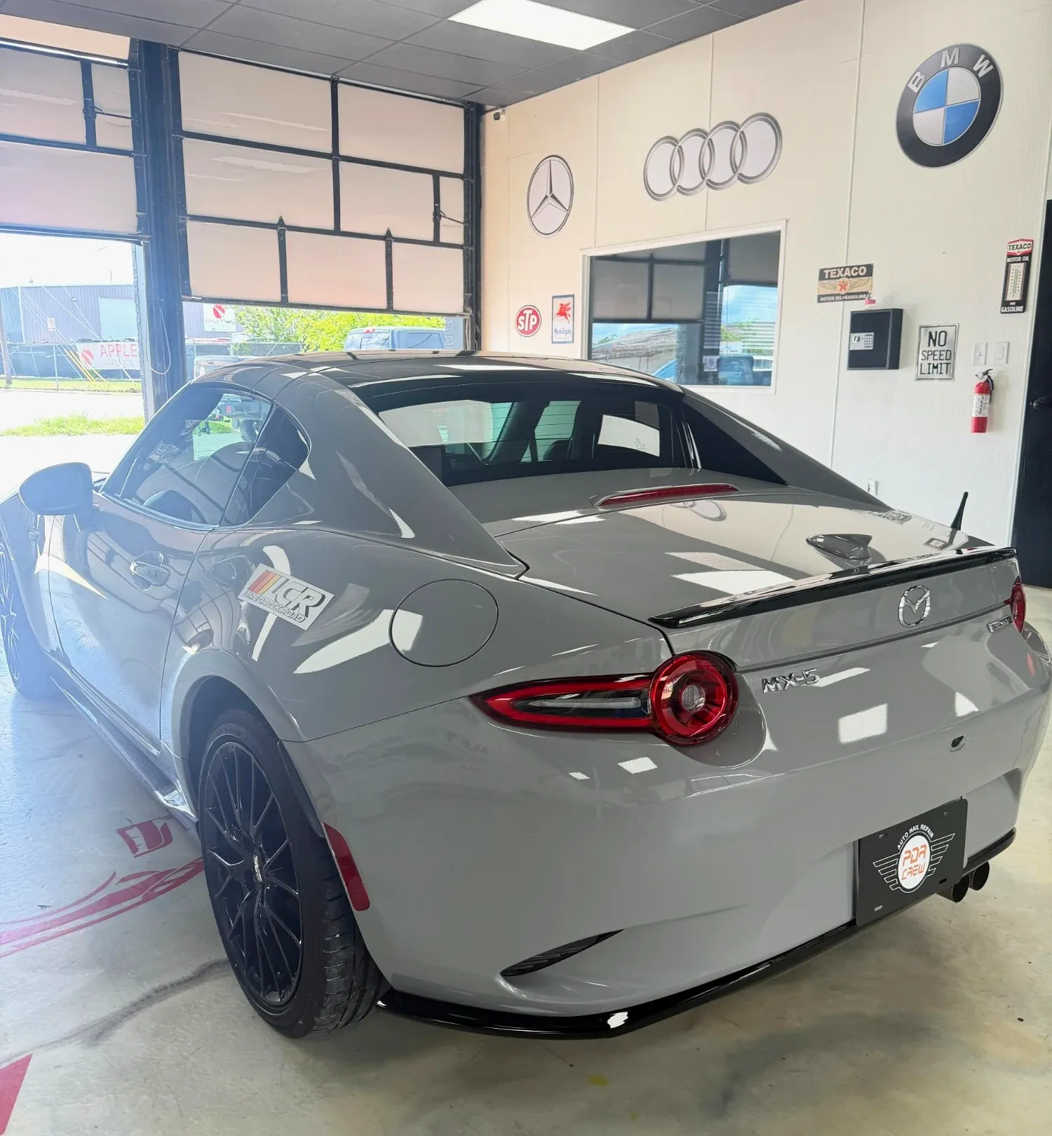 Gray Mazda MX-5 RF in the PDR Crew shop with a PDR Crew plate, after repair