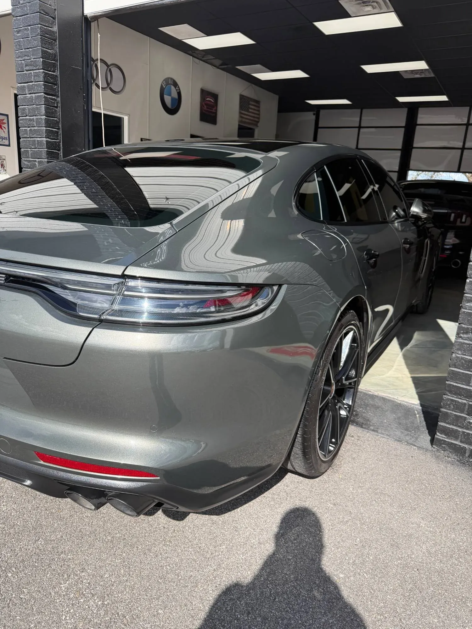 Gray Porsche Panamera rear quarter with clean reflections at the shop door
