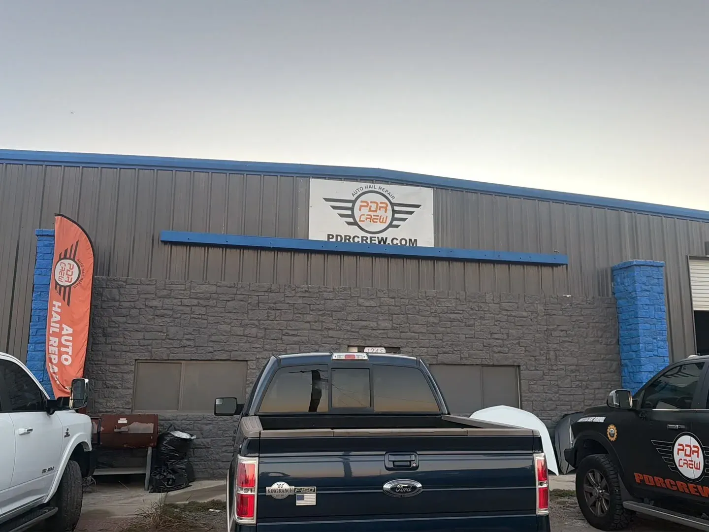 PDR Crew San Antonio shop front at 1245 E Loop 1604 S with the logo sign and an Auto Hail Repair flag