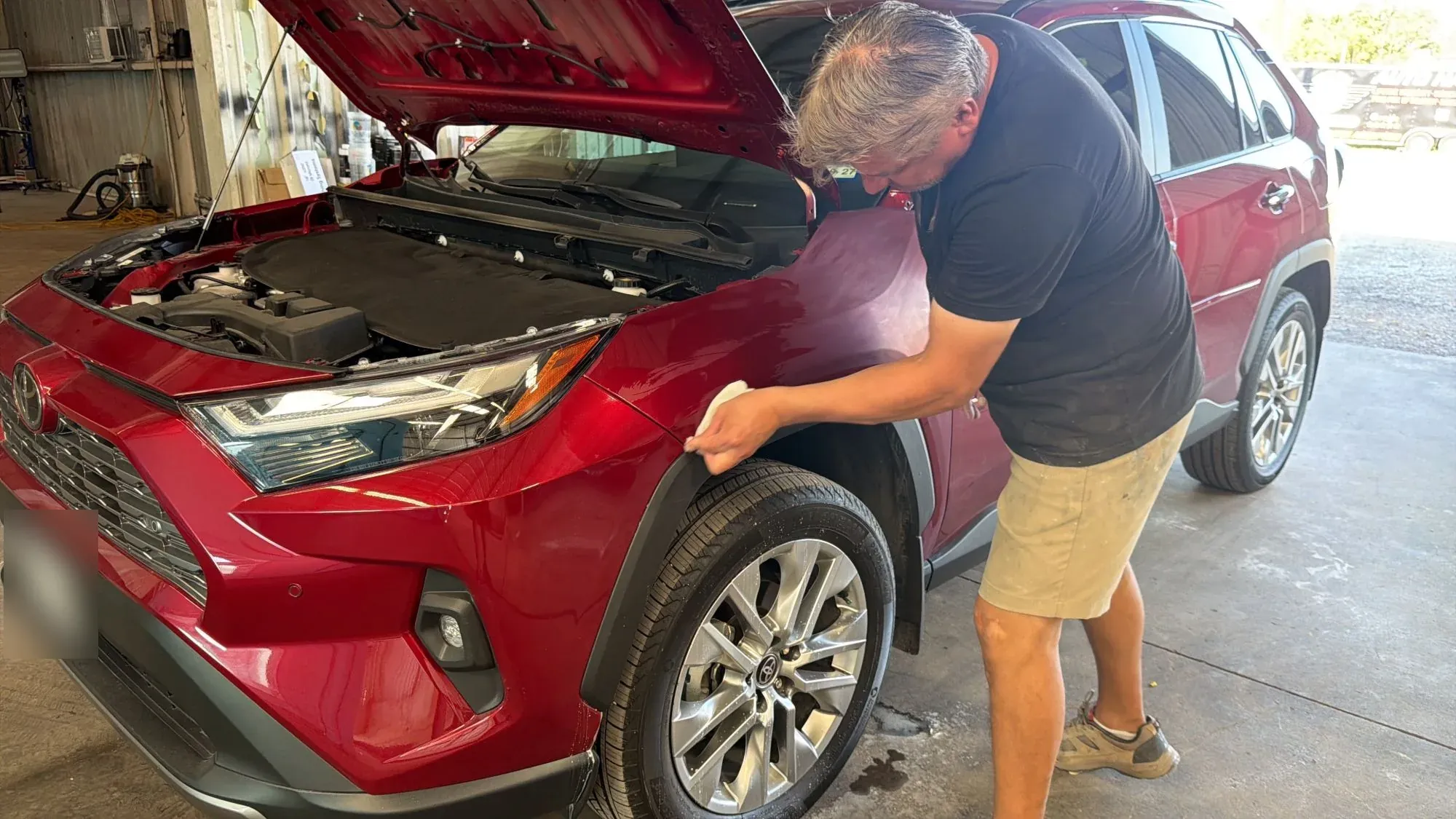 PDR Crew technician wiping down the fender of a red Toyota RAV4